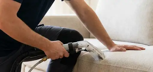 Professional upholstery cleaner deep-cleaning a fabric sofa with a handheld extraction tool, Stamford, CT.